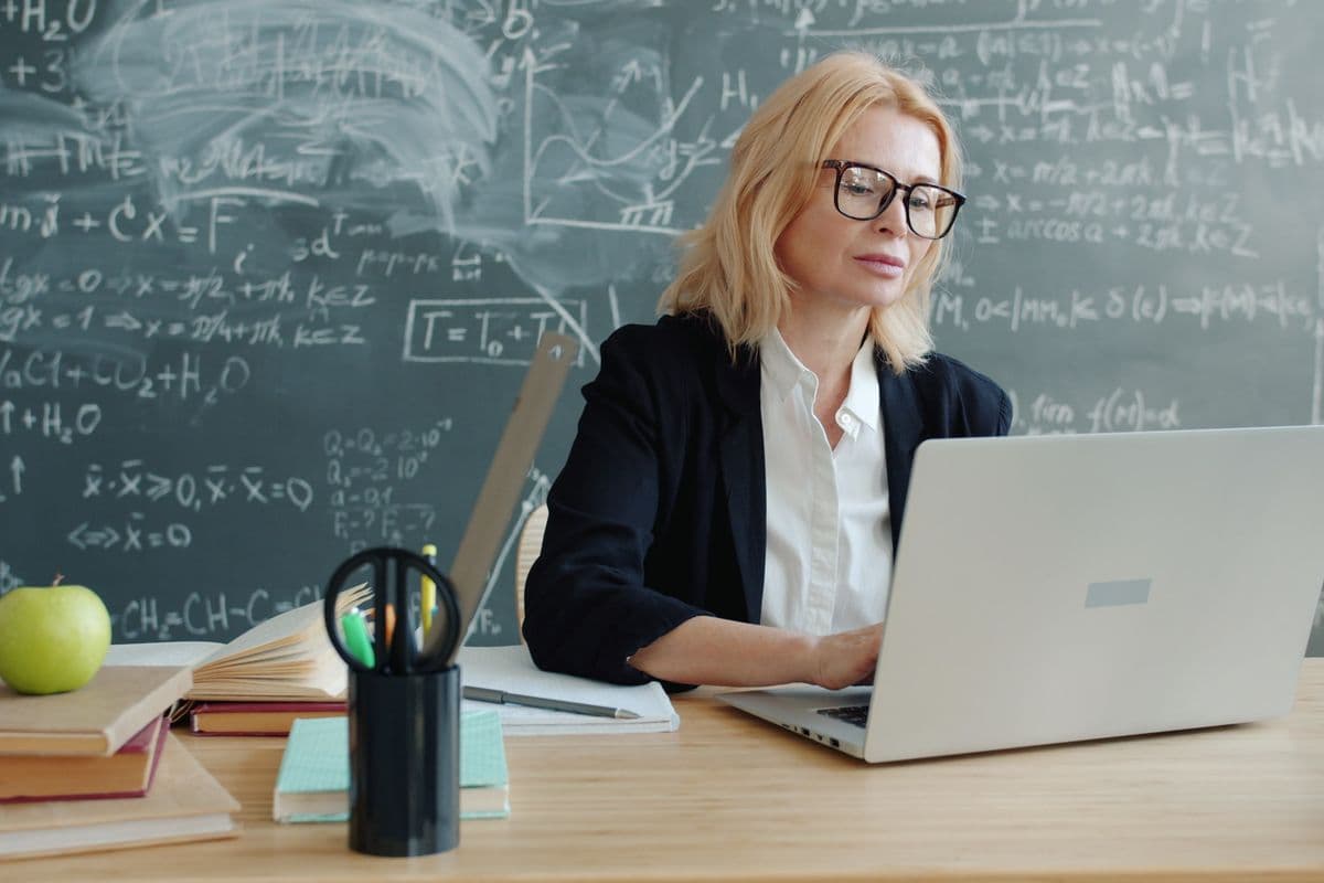 An instructor working on a laptop in a classroom